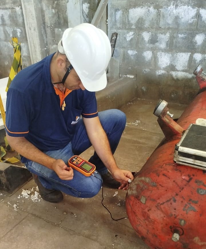 Equipe de engenheiros colaborando em um projeto em uma mesa com plantas e laptop